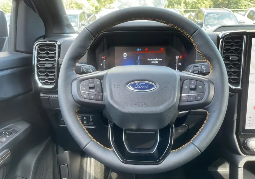 Vue intérieure centrée sur le volant cuir noir avec surpiqûres jaunes du Ford Ranger Wildtrak 2025.