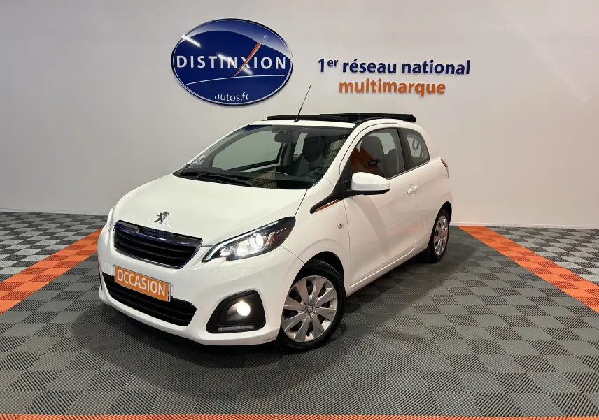 Peugeot 108 blanc vue 3/4 avant droit avec toit ouvrant et phares allumés en intérieur showroom.
