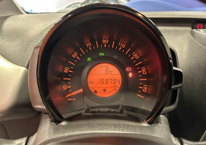 Vue rapprochée du compteur de vitesse orange du tableau de bord de la Peugeot 108 blanche de 2014.
