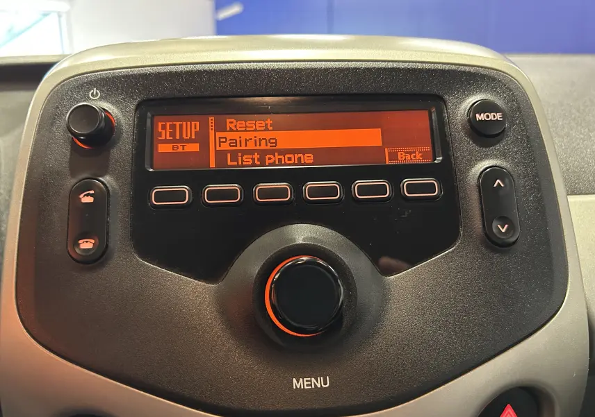 Détail de la console centrale noire de la Peugeot 108 blanche, affichant le menu Bluetooth en orange.