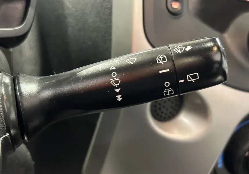 Gros plan sur la manette de commande des essuie-glaces noire dans l'habitacle d'une Peugeot 108 blanche.