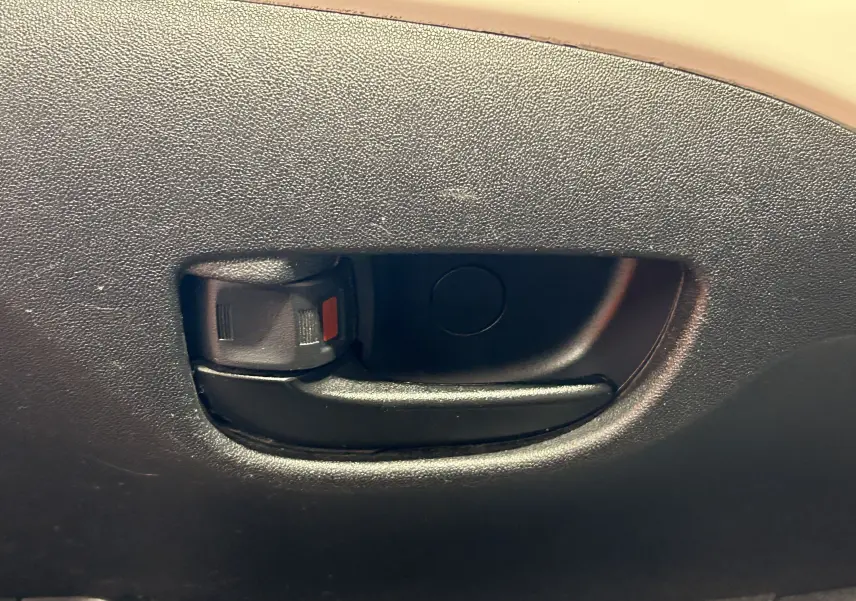 Poignée intérieure de porte noire du Peugeot 108 blanc, vue en gros plan sur la garniture intérieure.