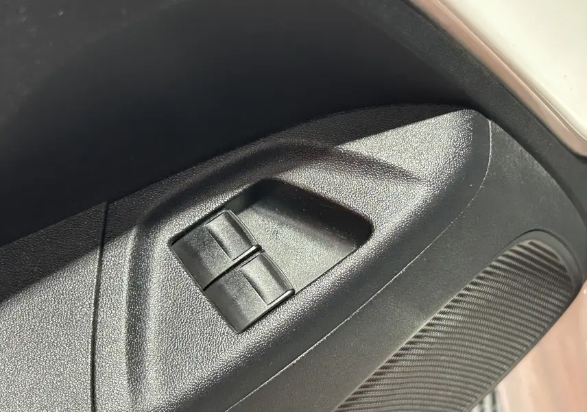 Gros plan sur les commandes de lève-vitres côté conducteur d'une Peugeot 108 blanche, version 2014.