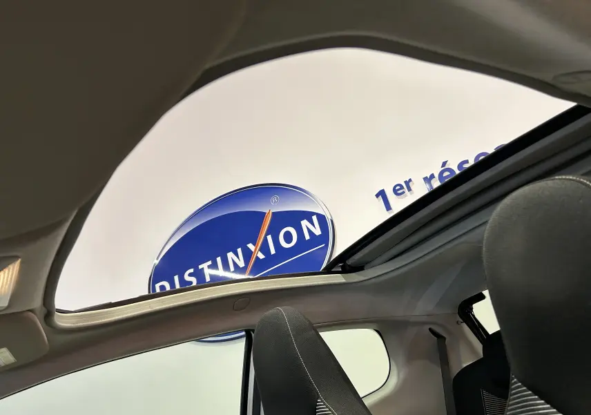 Vue intérieure du toit ouvrant panoramique d'une Peugeot 108 blanche, avec sièges avant en tissu noir visibles.