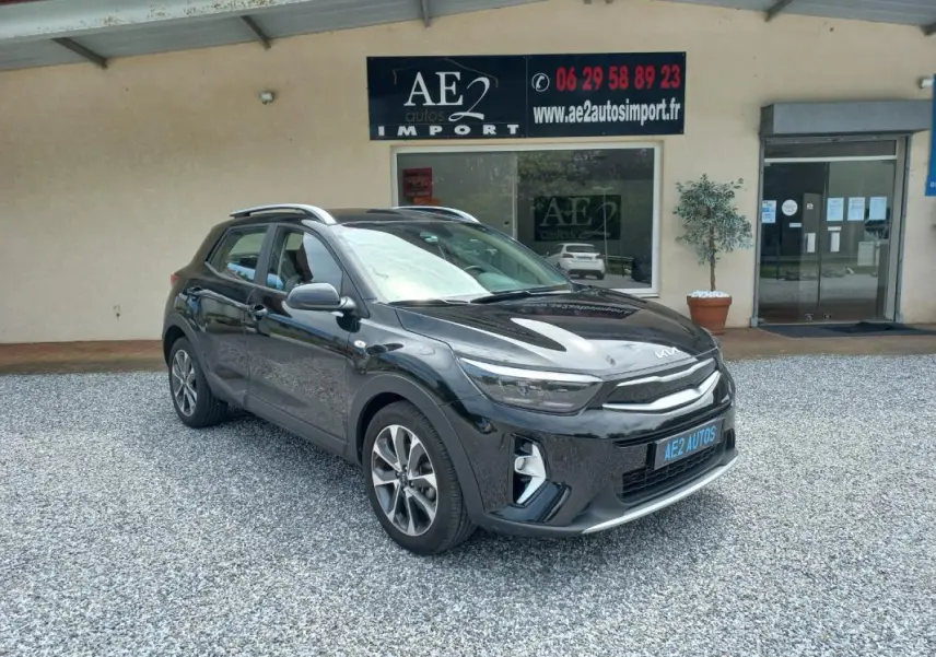 KIA STONIC noir 2025 en 3/4 avant droit, avec jantes alliage et toit ouvrant visible, stationné devant un garage.