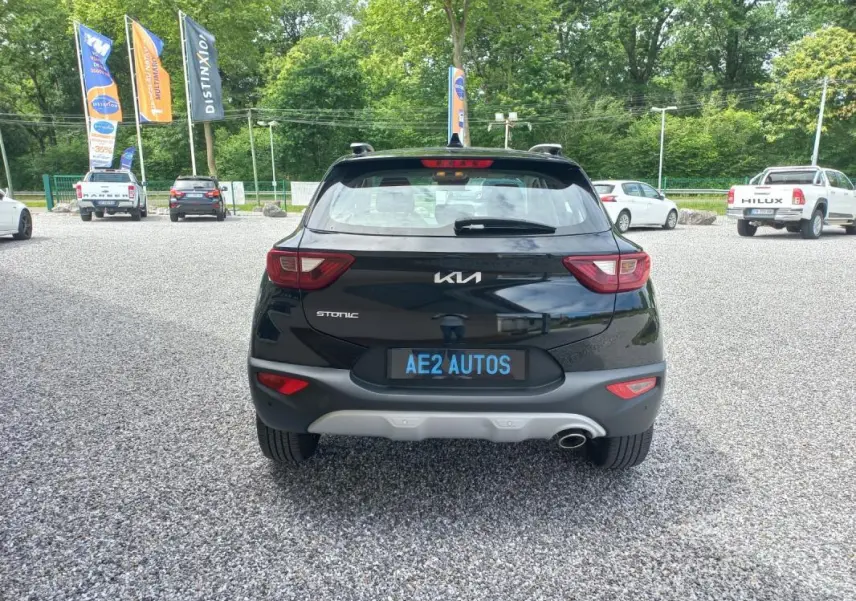 Vue arrière d’un KIA STONIC noir 2025 avec feux arrière distinctifs et plaque AE2 AUTOS sur parking gravillonné.