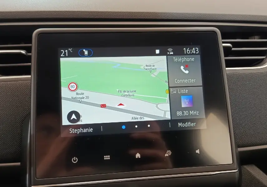 Écran tactile central du tableau de bord de la Renault ZOE blanche 2021 affichant la navigation et les options multimédia.