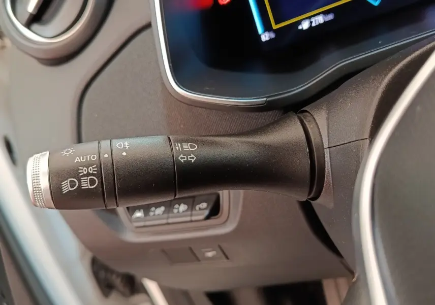 Gros plan sur la commande des phares et clignotants à gauche du volant dans l’habitacle d’une Renault ZOE blanche 2021.