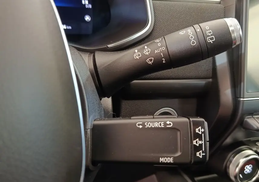 Détail du commodo noir multifonctions à gauche du volant dans l'habitacle de la Renault ZOE blanche 2021.