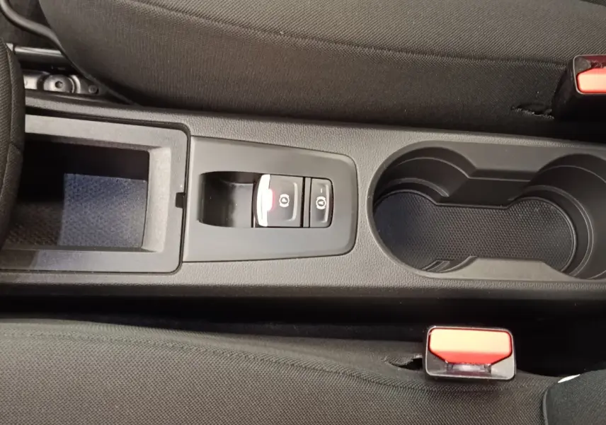 Vue rapprochée de la console centrale noire de la Renault ZOE blanche 2021 avec frein à main électrique et porte-gobelets.