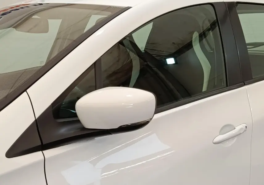 Gros plan sur le rétroviseur et la porte côté gauche d'une Renault ZOE blanche, intérieur visible à travers la vitre.