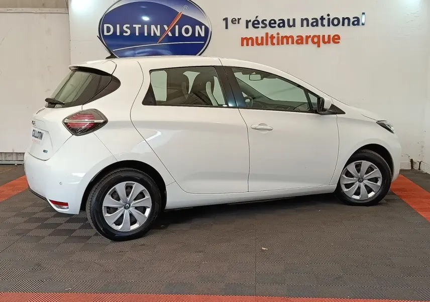 Profil droit d'une Renault ZOE Business Rev R110 blanche de 2021, avec jantes et feux arrière distinctifs visibles.