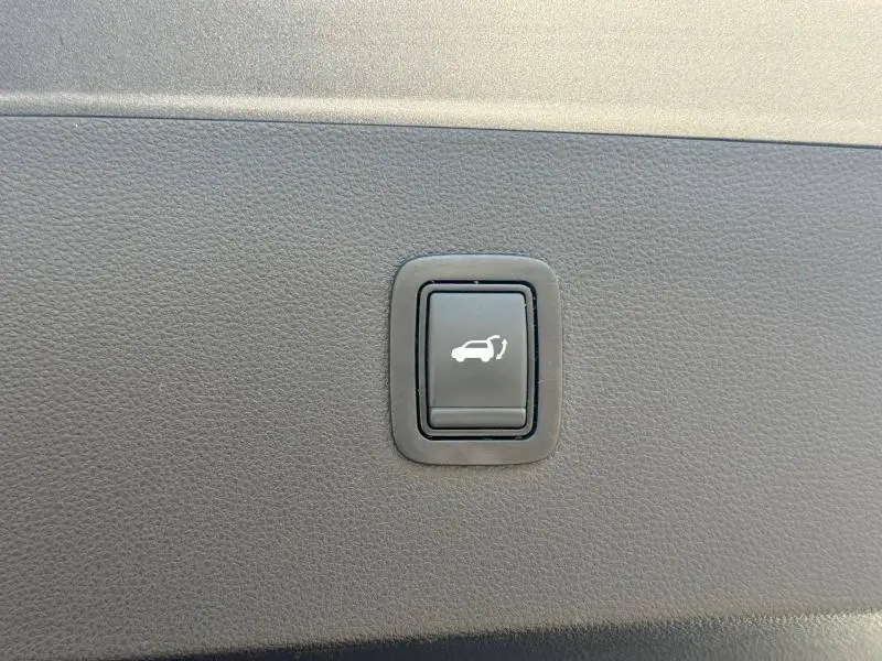 Bouton noir d'ouverture électrique du coffre sur panneau intérieur gris foncé du Dacia Bigster 2025.