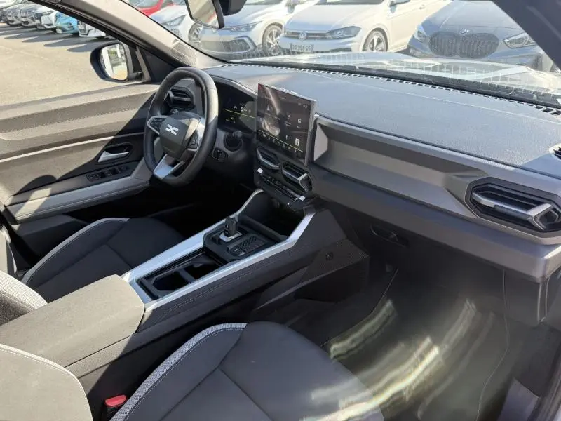 Vue intérieure côté conducteur du Dacia Bigster 2025 gris schiste, avec tableau de bord moderne et écran tactile central.