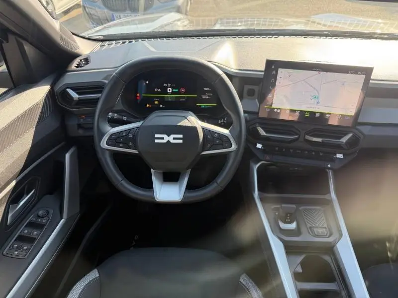 Vue intérieure frontale du tableau de bord du Dacia Bigster gris, avec volant multifonction et écran tactile GPS.