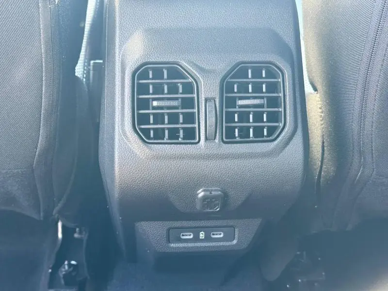 Vue rapprochée des aérateurs arrière et ports USB du Dacia Bigster 1.8 hybrid gris schiste entre les sièges avant.
