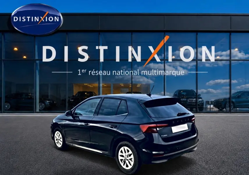 Skoda Fabia noire vue en 3/4 arrière droit, avec jantes alu et vitres arrière teintées devant showroom Distinxion.
