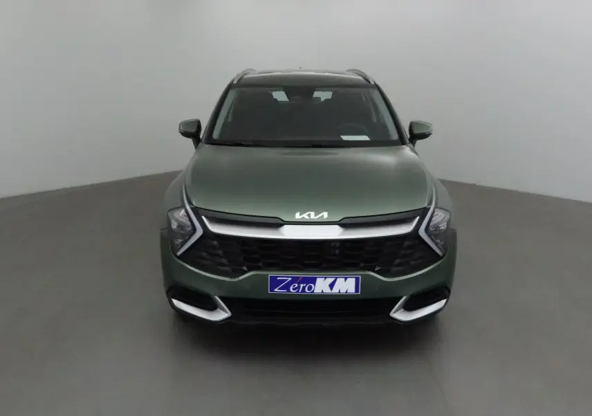 Vue frontale d'un KIA SPORTAGE 2025 vert Borneo avec calandre noire et phares LED en forme de flèche.