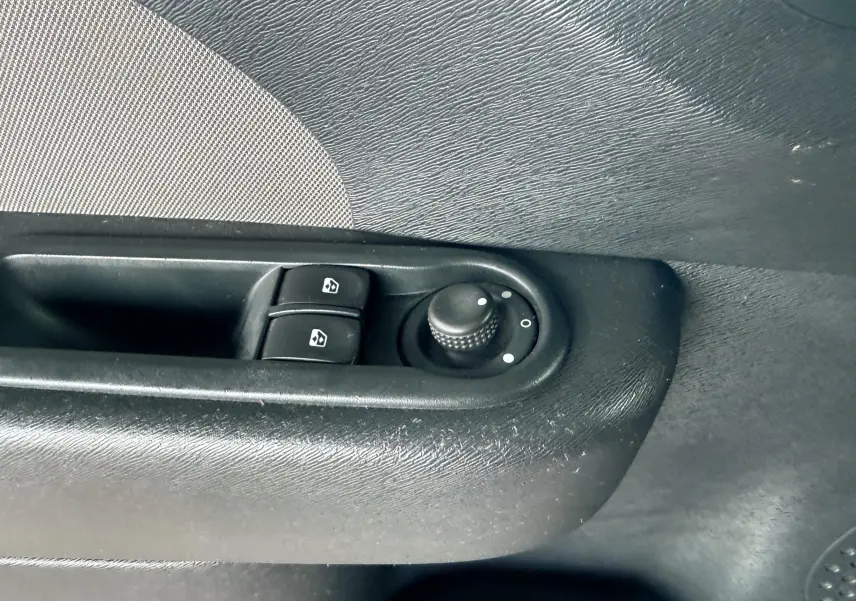 Gros plan sur les commandes de lève-vitres et réglage des rétroviseurs côté gauche d’une Renault Twingo II gris.