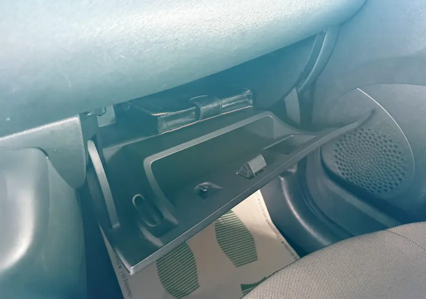 Gros plan sur la boîte à gants ouverte côté passager d'une Renault Twingo II gris, avec un étui noir à l'intérieur.