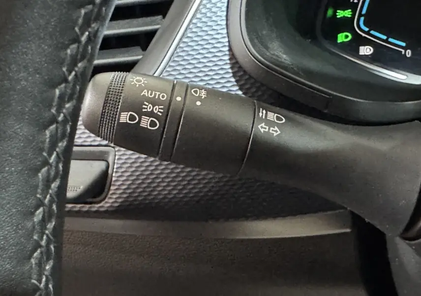 Gros plan sur la commande des phares et clignotants du Renault Arkana Business E-TECH 145, intérieur noir texturé.