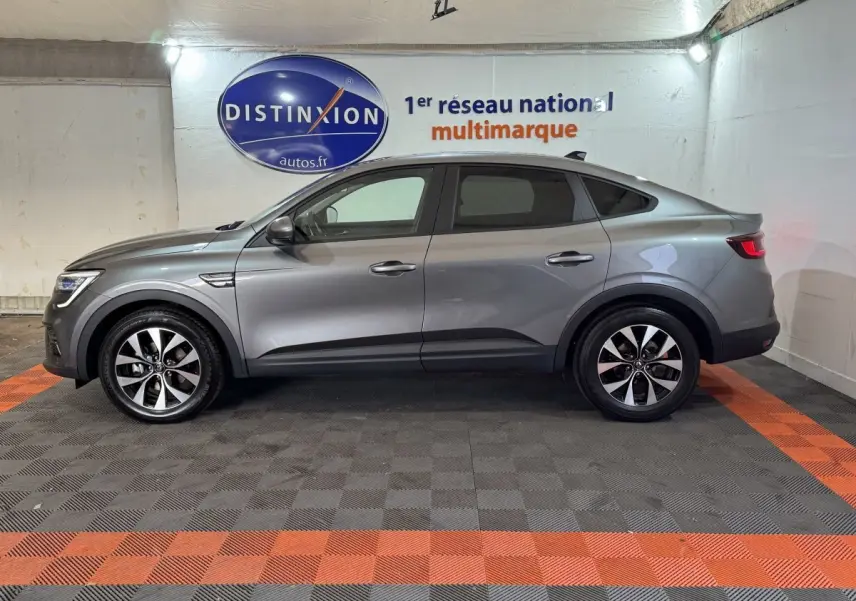 Renault Arkana Business E-TECH 145 gris foncé vue de profil côté gauche, en intérieur sur sol damier noir et orange.