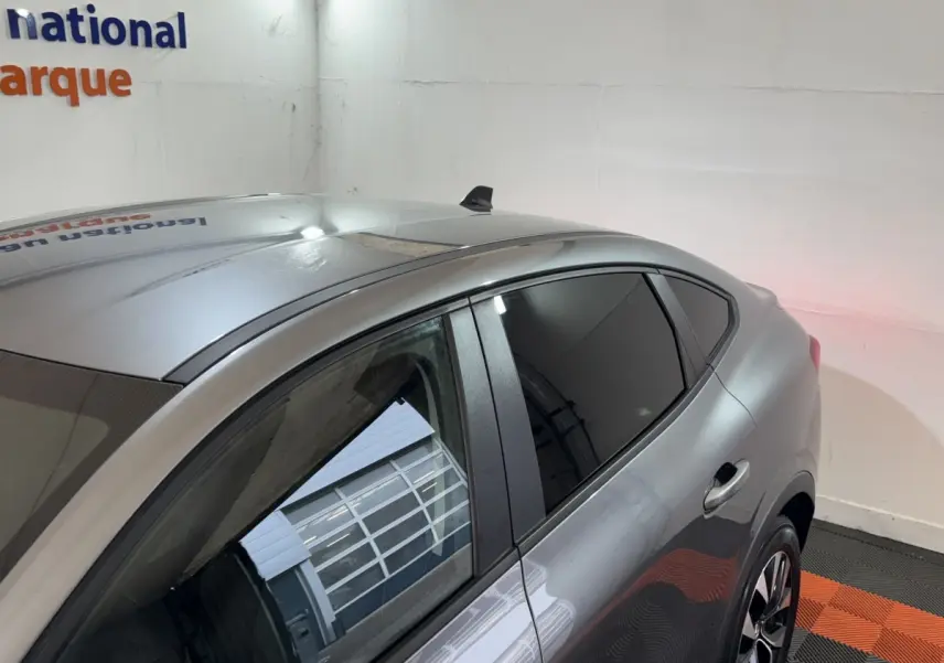 Vue 3/4 arrière du côté gauche d'une Renault Arkana Business E-TECH 145 gris foncé avec vitres teintées et jantes alliage.