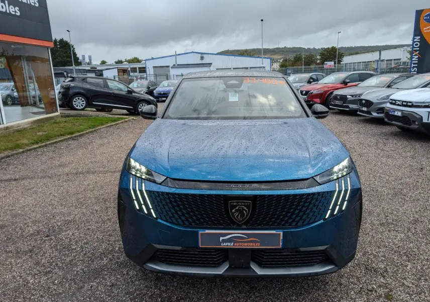 Peugeot 3008 GT bleu métallisé vue de face sous la pluie avec feux LED griffes allumés et calandre noire.
