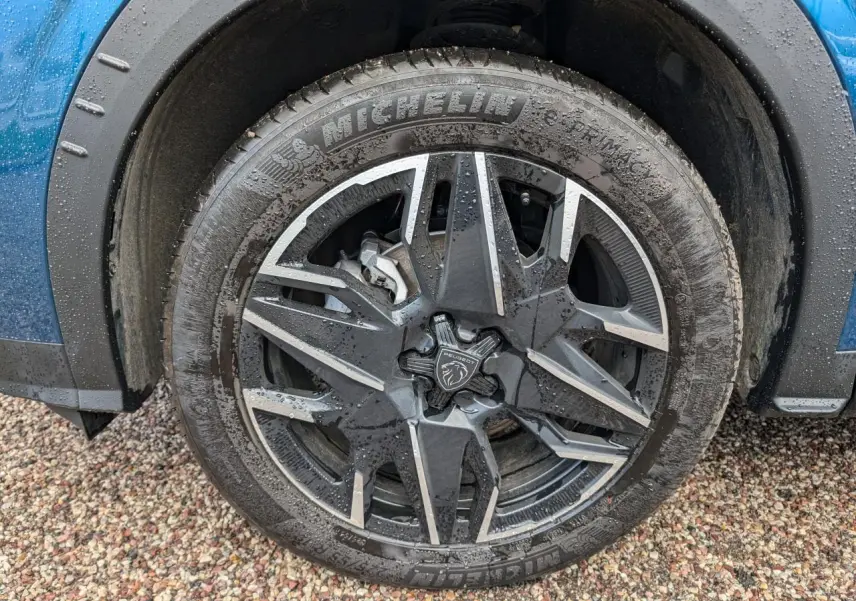 Gros plan sur la jante alliage 19'' diamantée noire et grise du Peugeot 3008 bleu métallisé, roue avant droite.