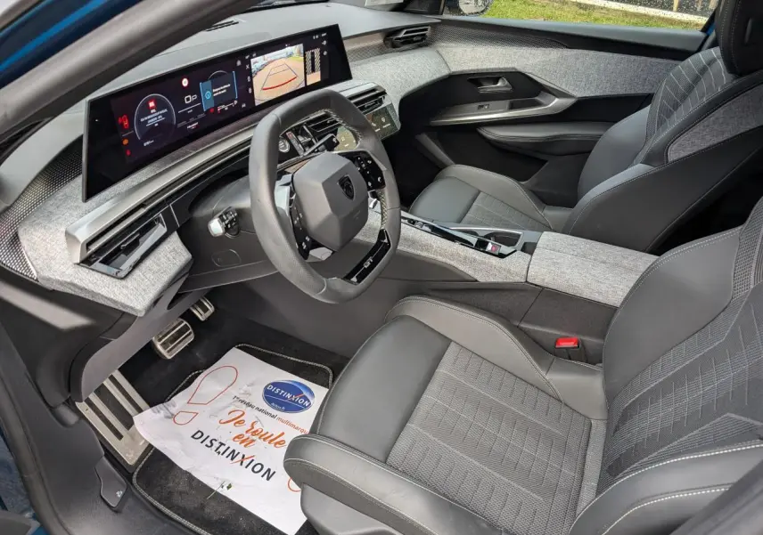 Intérieur avant du Peugeot 3008 Hybrid 2025, avec tableau de bord numérique panoramique et sellerie tissu gris.