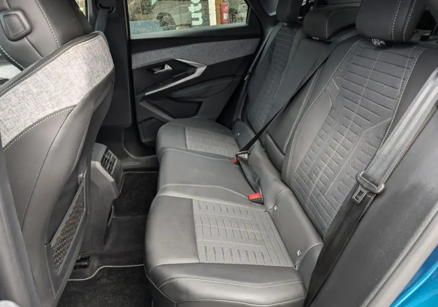 Vue intérieure côté droit sur la banquette arrière gris foncé et tissu chiné du Peugeot 3008 GT bleu métallisé 2025.