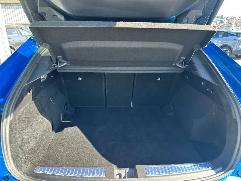 Coffre ouvert vu de l'arrière d'une Renault Rafale 1.2 E-Tech bleu sommet métallisé, montrant un espace de chargement spacieux et propre.