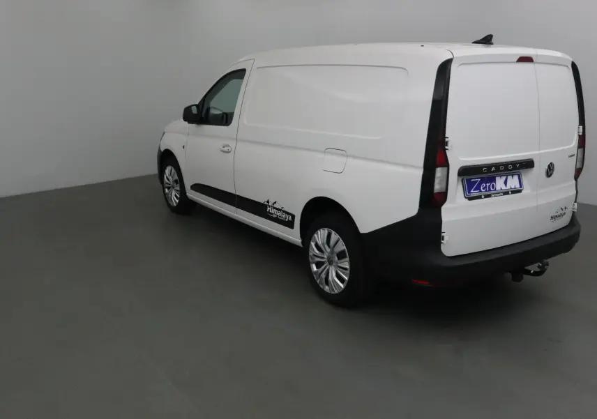 Vue 3/4 arrière droite d'un utilitaire Volkswagen Caddy Maxi blanc avec logo Himalaya et attelage visible.