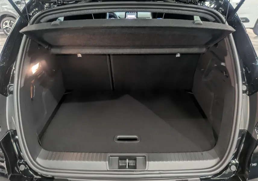 Coffre ouvert vu de l'arrière du Renault Captur E-TECH Full Hybrid noir étoilé, montrant un espace de chargement vide et éclairé.