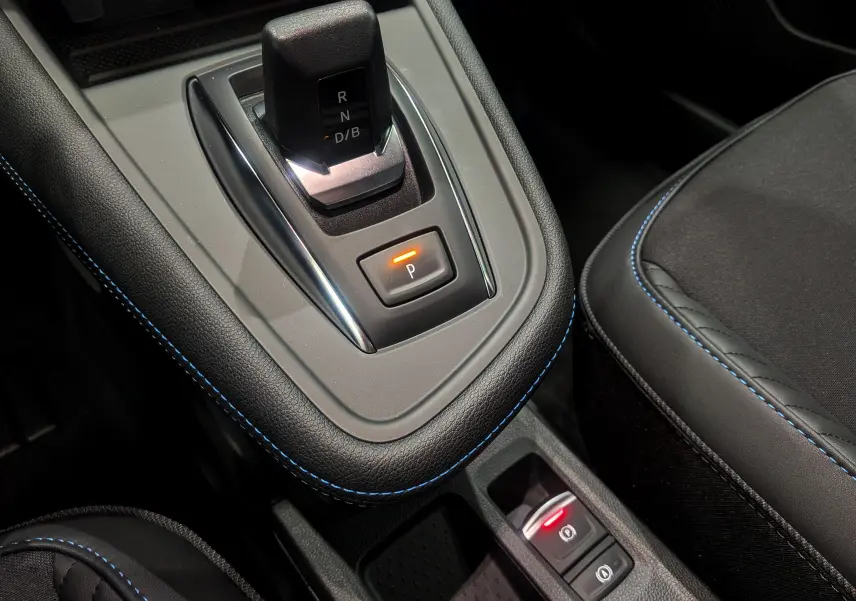 Gros plan sur la console centrale noire étoilé du Renault Captur E-TECH avec levier de vitesses et bouton de frein à main électrique.