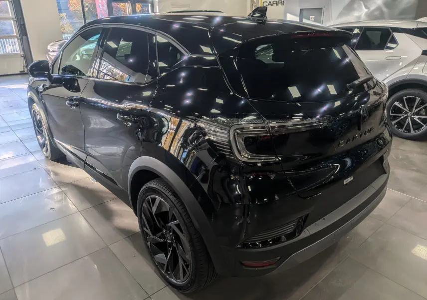 Vue 3/4 arrière droite du Renault Captur E-TECH Full Hybrid noir étoilé, soulignant ses jantes noires et ses feux arrière LED.