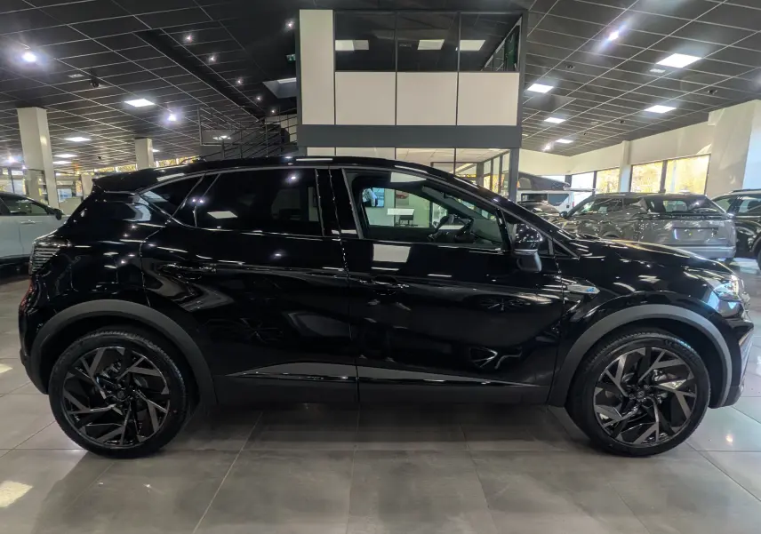 Profil côté gauche d'un Renault Captur E-TECH Full Hybrid 160 CH esprit Alpine noir étoilé en showroom, roues noires distinctives.