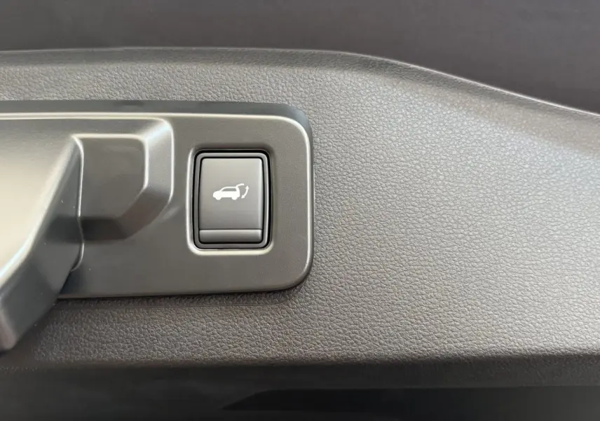 Gros plan sur le bouton d'ouverture électrique du coffre dans l'habitacle du Renault Espace blanc.