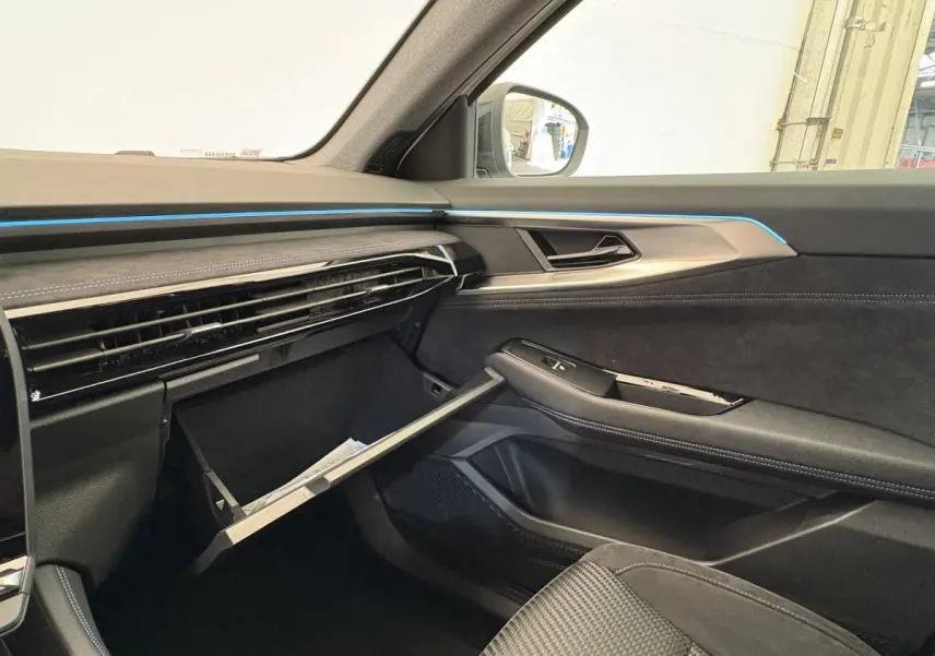 Vue intérieure côté passager du tableau de bord noir avec éclairage bleu et boîte à gants ouverte du Renault Espace 2025 esprit Alpine.