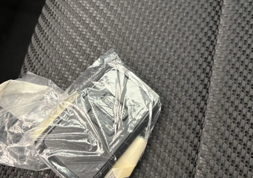 Télécommande Renault Espace 2025 en plastique transparent posée sur un siège tissu gris à motifs géométriques.