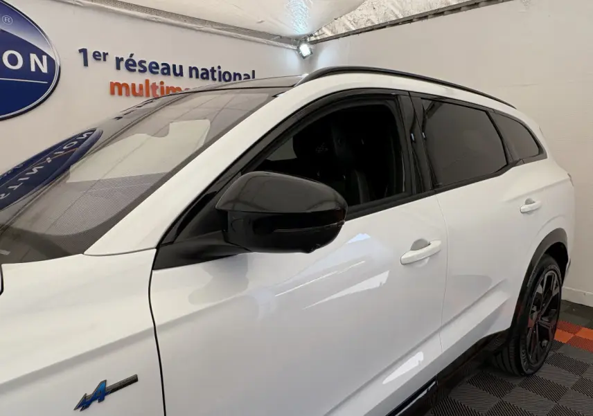 Vue côté gauche avant d'un Renault Espace blanc esprit Alpine 7 places avec rétroviseur noir et vitres teintées.