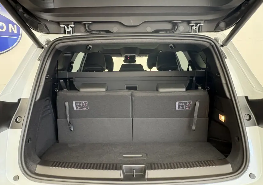 Coffre ouvert vu de l'arrière d'un Renault Espace blanc avec sièges arrière relevés et habillage intérieur noir.