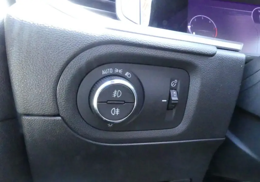 Gros plan sur le bouton de commande des phares et feux antibrouillard à gauche du tableau de bord de l'Opel Grandland 2024.