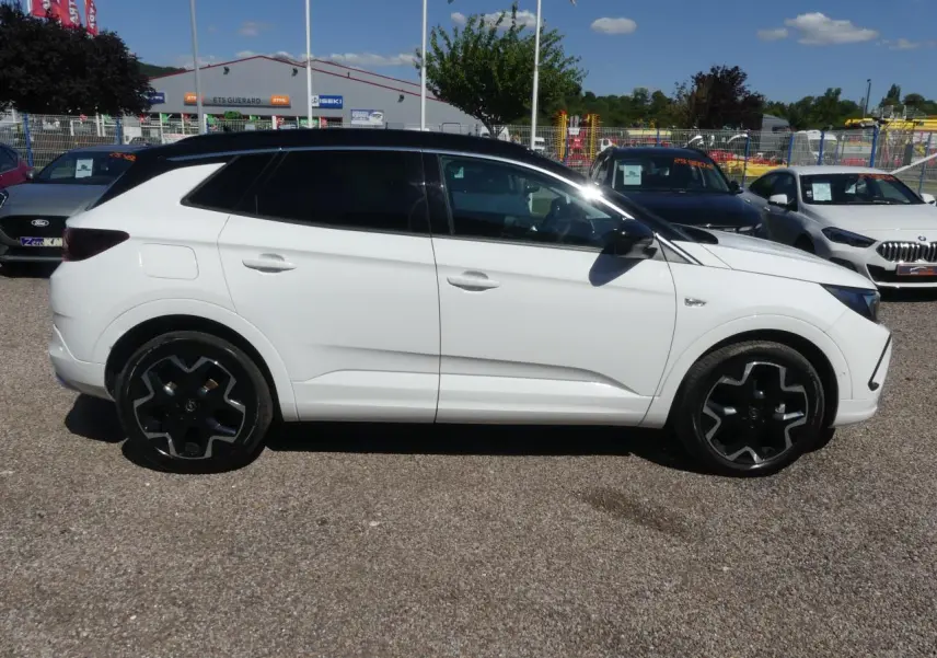 Opel Grandland blanc métallisé vu de profil côté gauche avec toit noir et jantes alliage noires.
