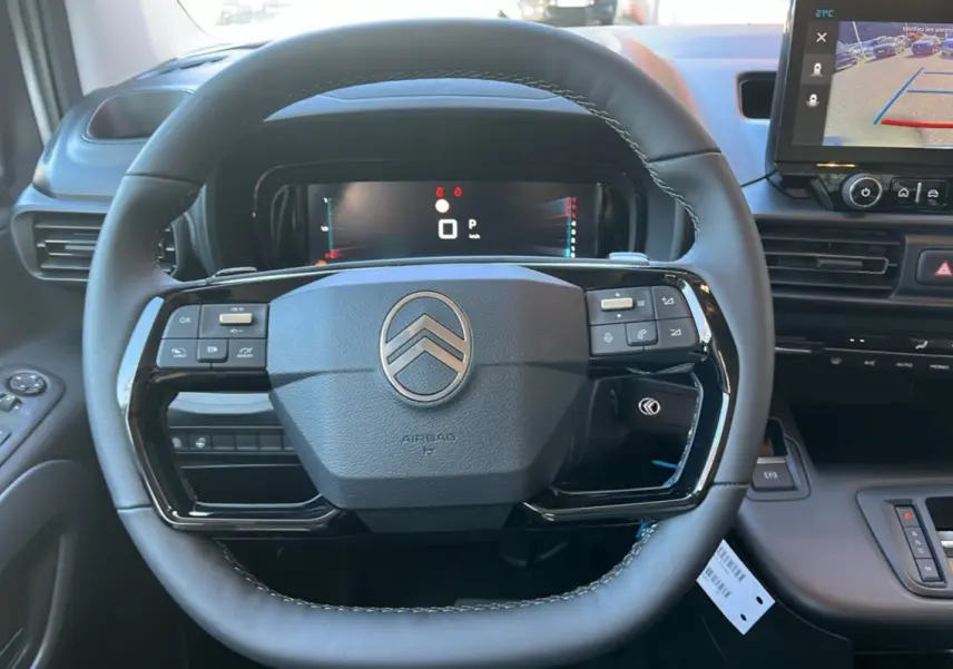 Vue rapprochée du volant cuir multifonctions Citroën Berlingo 2025 avec écran numérique et caméra de recul affichée.