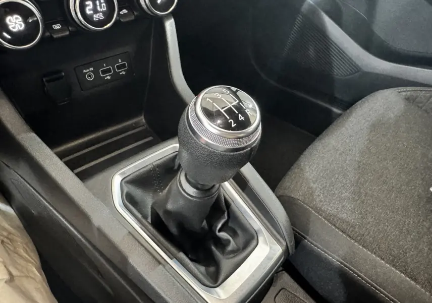 Gros plan sur le levier de vitesse manuel noir et argenté dans l'habitacle sombre de la Renault Clio Business TCe 100.