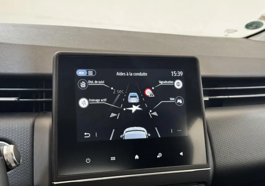 Écran tactile central affichant les aides à la conduite dans l’habitacle d’une Renault Clio gris clair, vue de face.