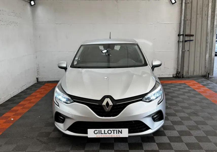 Vue frontale d'une Renault Clio Business TCe 100 gris clair avec phares LED allumés dans un garage.