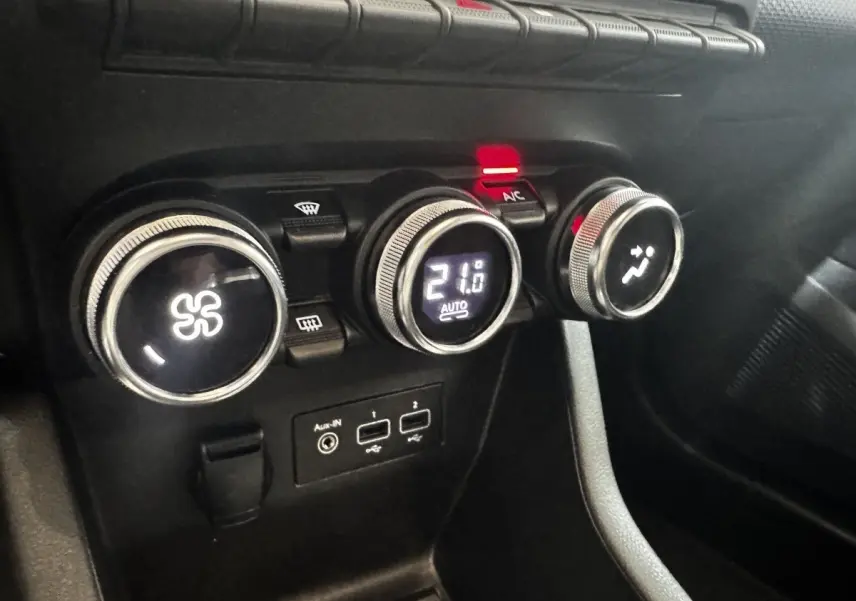 Gros plan sur les commandes de climatisation et les ports USB d’une Renault Clio Business TCe 100 gris clair, intérieur noir.