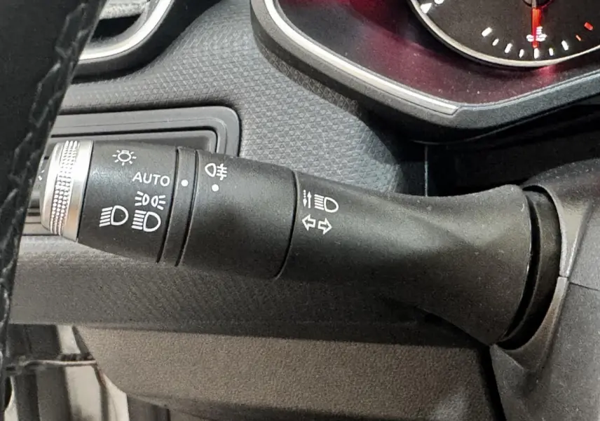 Gros plan sur la commande des phares et clignotants du tableau de bord d’une Renault Clio Business gris clair de 2020.